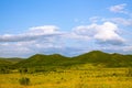 Hills with green grass and blue sky with white puffy clouds Royalty Free Stock Photo