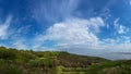 Hills with green grass and trees on the coast with blue sky and clouds. Royalty Free Stock Photo