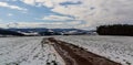 Hills and trees in winter Czech landscape with dirt road and snow field Royalty Free Stock Photo