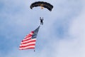 Paratrooper jumping with american flag attached to him.