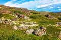 Hillside, green grass, stones, blue sky Royalty Free Stock Photo