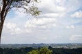 Hillside landscape with trees and distant town under cloudy sky Royalty Free Stock Photo