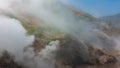 The hillside is shrouded in thick steam from an erupting geyser