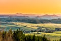 Hilly landscape illuminated by evening sunset. Green grass fields and hills on the horizont. Vivid spring rural Royalty Free Stock Photo