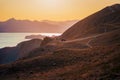 Hilly landscape by the sea in a bright orange sunset. Layers of mountains at sunset, background image