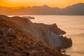 Hilly landscape by the sea in a bright orange sunset. Layers of mountains at sunset, background image