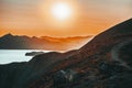 Hilly landscape by the sea in a bright orange sunset. Layers of mountains at sunset, background image