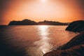 Hilly landscape by the sea in a bright orange sunset. Layers of mountains at sunset, background image