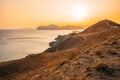 Hilly landscape by the sea in a bright orange sunset. Layers of mountains at sunset, background image