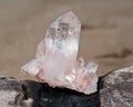 Himalayan clear quartz cluster with hematite inclusions on wet sand on the beach Royalty Free Stock Photo