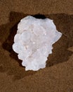 Himalayan clear quartz cluster with hematite inclusions on wet sand on the beach Royalty Free Stock Photo