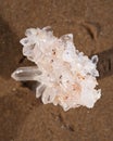 Himalayan clear quartz cluster with hematite inclusions on wet sand on the beach Royalty Free Stock Photo