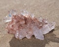 Himalayan clear quartz cluster with hematite inclusions on wet sand on the beach Royalty Free Stock Photo