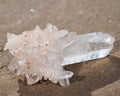 Himalayan clear quartz cluster with hematite inclusions on wet sand on the beach Royalty Free Stock Photo