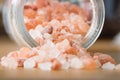 Himalayan pink rock salt in a bottle container on a wooden surface.