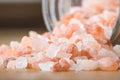 Himalayan pink rock salt in a bottle container on a wooden surface.