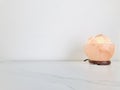 Himalayan pink salt lamp carved as a bowl on white marble table and white wall background.