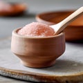 Himalayan pink salt in a wooden cup with a wooden spoon on the table. Blurred background with crockery. AI generated