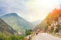 Himalayas landscape with two cyclist, mountains, road, river and clouds