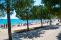 City public beach with pine trees. Vacationers on beautiful clean sand and pebble beach. Himare, Albania