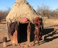 Himba woman standing in front of hut