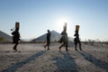 Himba women walking back after collecting water in containers on their heads, Epupa, Kunene Region, Namibia.