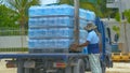 CLOSE UP: Local man helps crane operator pick up a pallet full of water bottles