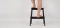 Hind legs and bare feet on a wooden stool or ladder on a white background
