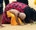 Hindu devotees in Katagama Dewalaya, Mother, and her son kneel down on the sand and worships the God of Kataragama