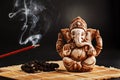 Hindu god Ganesh on a black background. Rudraksha statue and rosary on a wooden table with a red incense stick and incense smoke Royalty Free Stock Photo