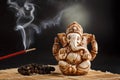 Hindu god Ganesh on a black background. Rudraksha statue and rosary on a wooden table with a red incense stick and incense smoke Royalty Free Stock Photo