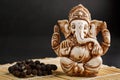 Hindu god Ganesh on a black background. Rudraksha statue and rosary on a wooden table with a red incense stick and incense smoke Royalty Free Stock Photo