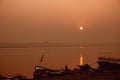 A hindu man praying during sunrise on the river Ganges in Varanasi, India. Fog, seagulls and boat silhouettes Royalty Free Stock Photo