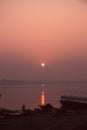 A hindu man praying during sunrise on the river Ganges in Varanasi, India. Fog, seagulls and boat silhouettes Royalty Free Stock Photo