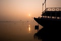 A hindu man praying during sunrise on the river Ganges in Varanasi, India. Fog, seagulls and boat silhouettes Royalty Free Stock Photo