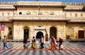 Hindu people rush past the entrance of the yellow wall temple