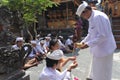 Hindu priest blessing Balinese family celebrating Galungan Kuningan holidays in Bali Indonesia