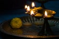 hindu puja essential panch pradeep or five headed oil lamp burning with glowing flame with marigold flowers kept on brass plate.