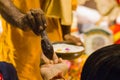 Hindu puja ritual of pushpanjali, where the priest is giving charanamrita or sacred food made of milk on hands of devotees.this