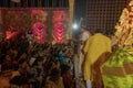 Hindu purohit spraying Holy water, called shantir jol, upon devotees worshipping Goddess Durga, inside decorated Durga Puja Pandal