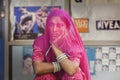 Hindu women covered by a violet scarf from a conservative fam in front of a billboard full of pictures of women in modern clothing