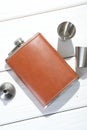 Hip flask, cups and funnel on white wooden table, flat lay Royalty Free Stock Photo