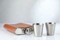 Hip flask and cups on white table. Space for text Royalty Free Stock Photo