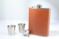 Hip flask, funnel and cups on white table Royalty Free Stock Photo