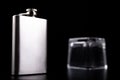 Hip flask and glass made of thick glass inverted. Bartender accessories on the table