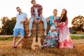 Hippie friends with guitar in a wheat field