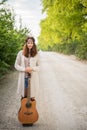 Hippie girl with the guitar standing on rural road Royalty Free Stock Photo