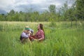 Hippie guy and girl listen to music on a vintage cassette recorder sitting in the grass Royalty Free Stock Photo