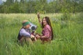 Hippie guy and girl listen to rock music on a vintage cassette recorder sitting in the grass Royalty Free Stock Photo