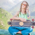 Hippie handsome man with skateboard and mobilephone listening to music Royalty Free Stock Photo